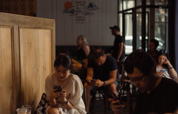 people sitting with smartphones in restaurant